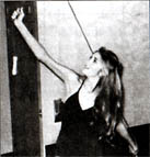 figure facing away from wall demonstrating arm pull